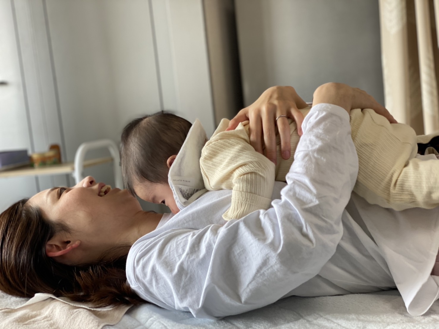 仰向けで赤ちゃんをだくお母さん